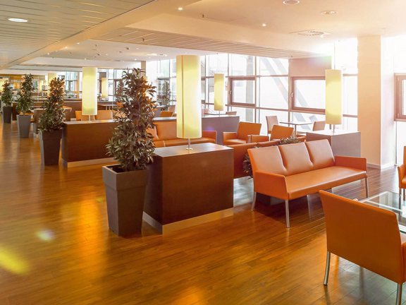 Lounge Bereiche mit mehreren Sofas und Sesseln, die durch niedrige Konsolentische leicht voneinander abgetrennt sind. 